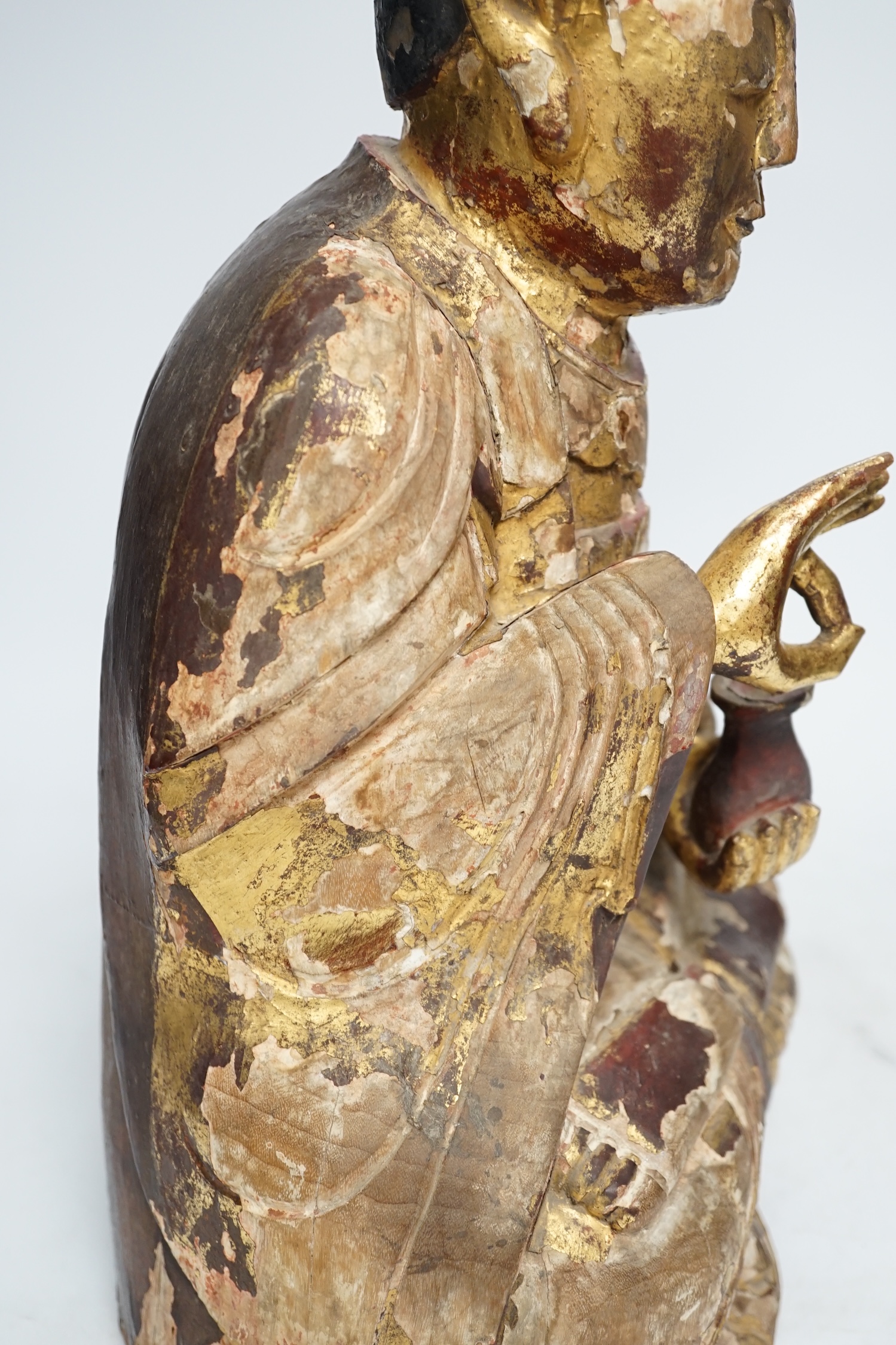 A Chinese gilt lacquered wooden figure of Buddha, possibly Yuan to Ming, 42cm high. Condition - poor to fair, losses to lacquer overall